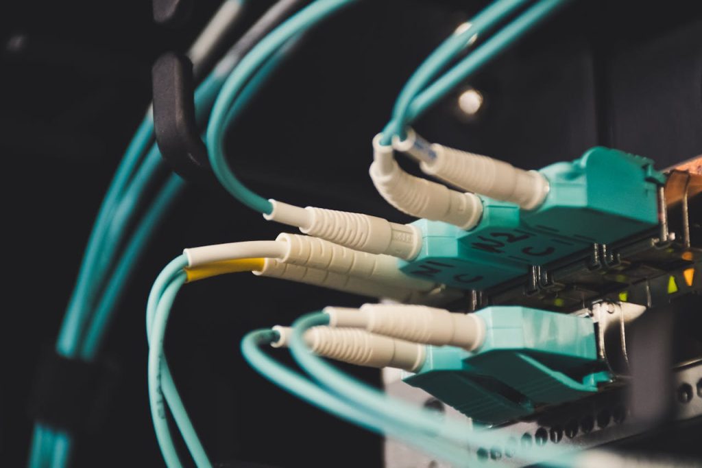 close-up-photo-of-plugged-cables-1624895 Detailed view of fiber optic cables and ports in a server room, showcasing connectivity.